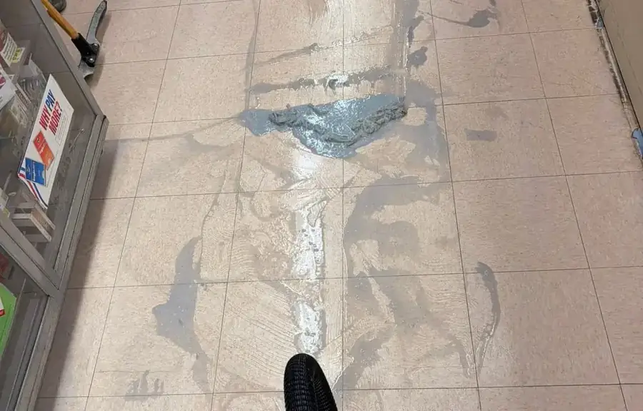 Old floor finish being stripped and vacuumed up in a store aisle