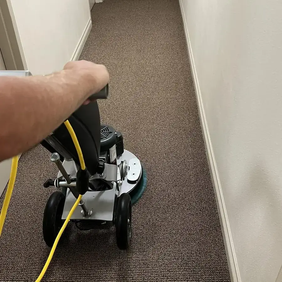 Technician running a low-moisture carpet cleaning machine down a commercial hallway
